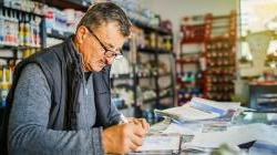 Senior man entrepreneur at his office store by the table accounting 