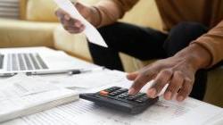 Man using calculator and accounting for expenses at coffee table