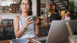 Latina business owner sitting her restaurant smiling